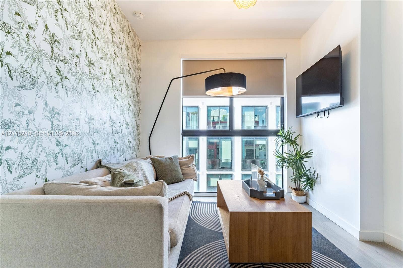 136 NW 26th Street, #507, Miami, FL 33127 Floor-to-ceiling windows with roller shades, patterned accent wall, and wood-finish flooring