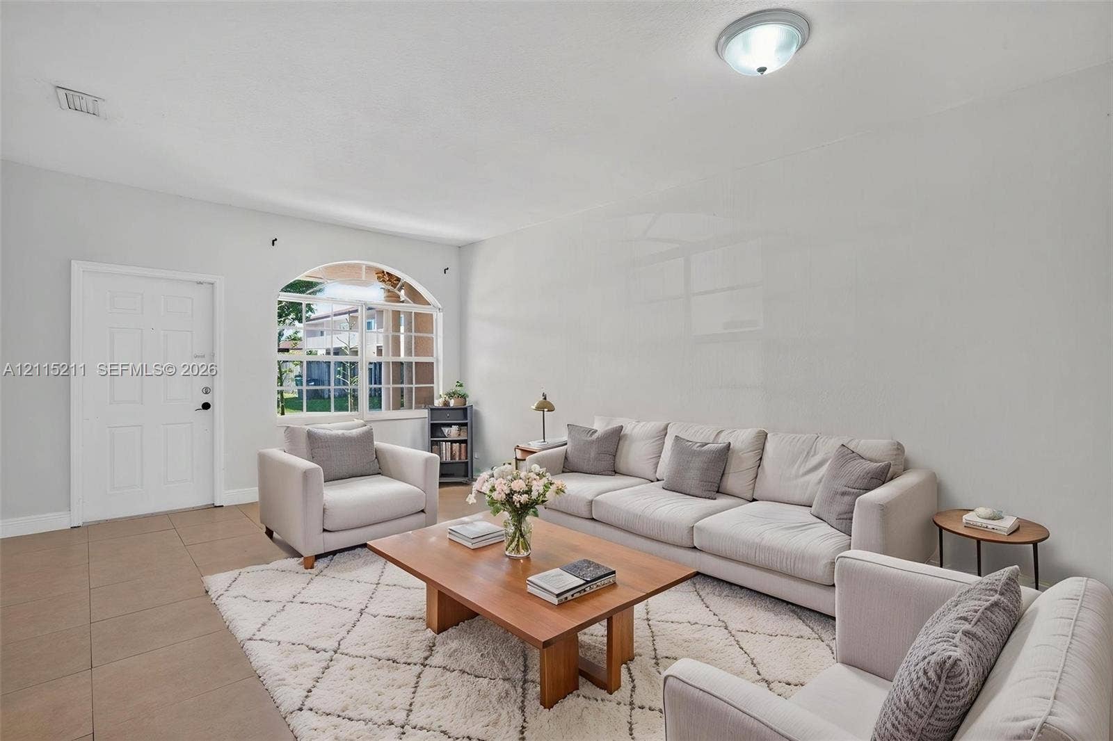 Neutral-toned tile flooring, arched window with a grid pattern, and flush-mount overhead lighting