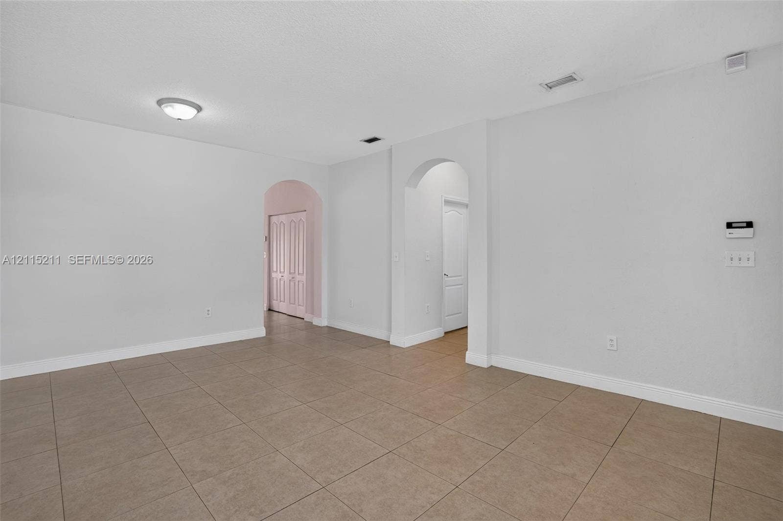 Open-concept interior featuring large-format neutral tile flooring and arched doorways