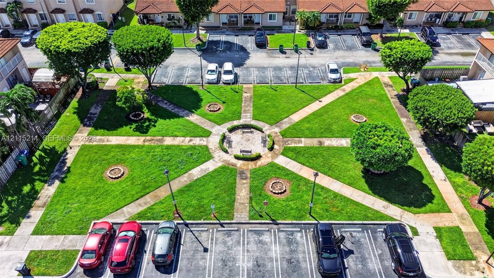 Central courtyard featuring manicured lawn, paved walkways, mature trees, and a circular seating area