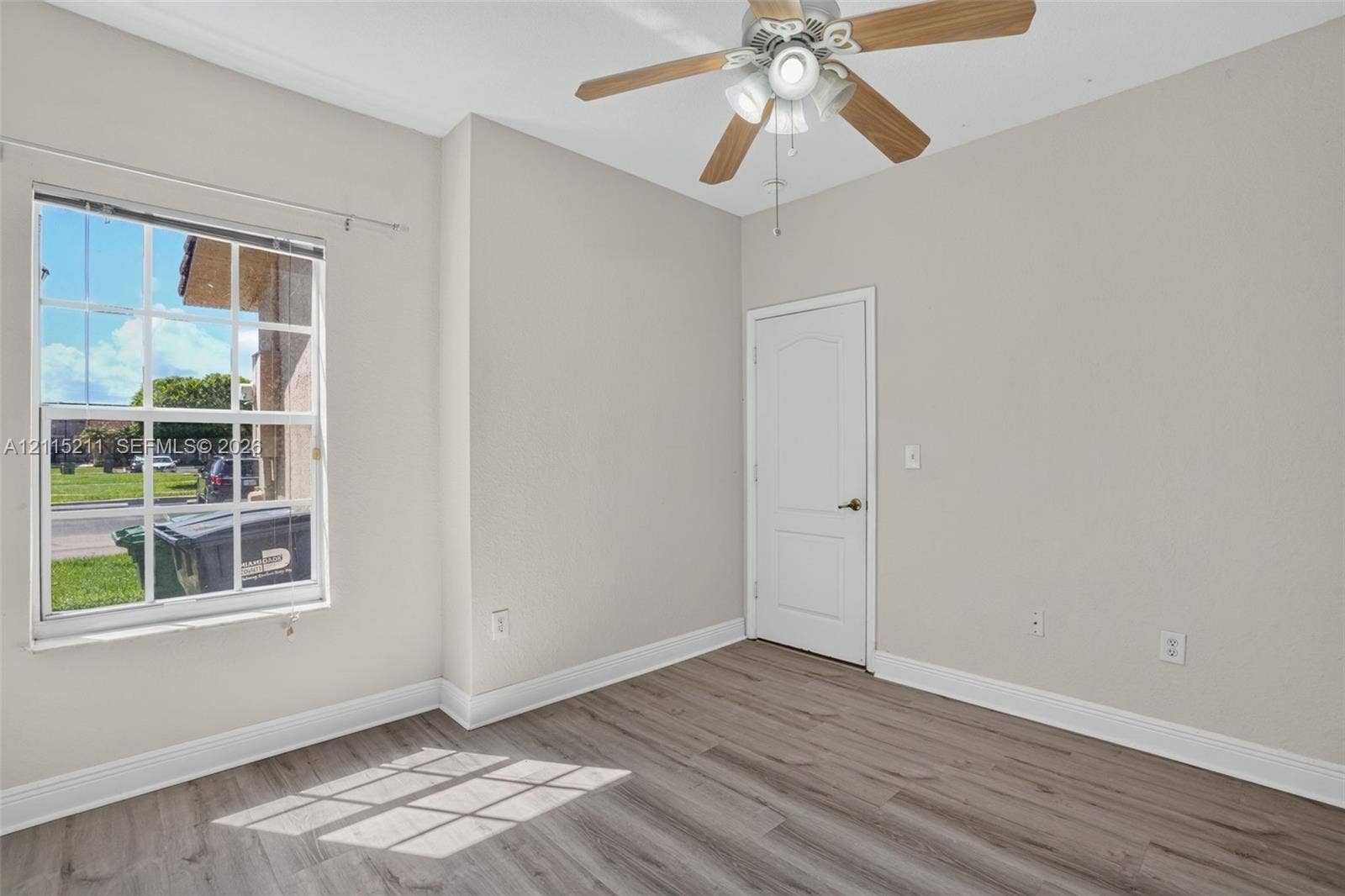 Interior space featuring wood-finish flooring, a multi-pane window, and a ceiling fan with integrated lighting