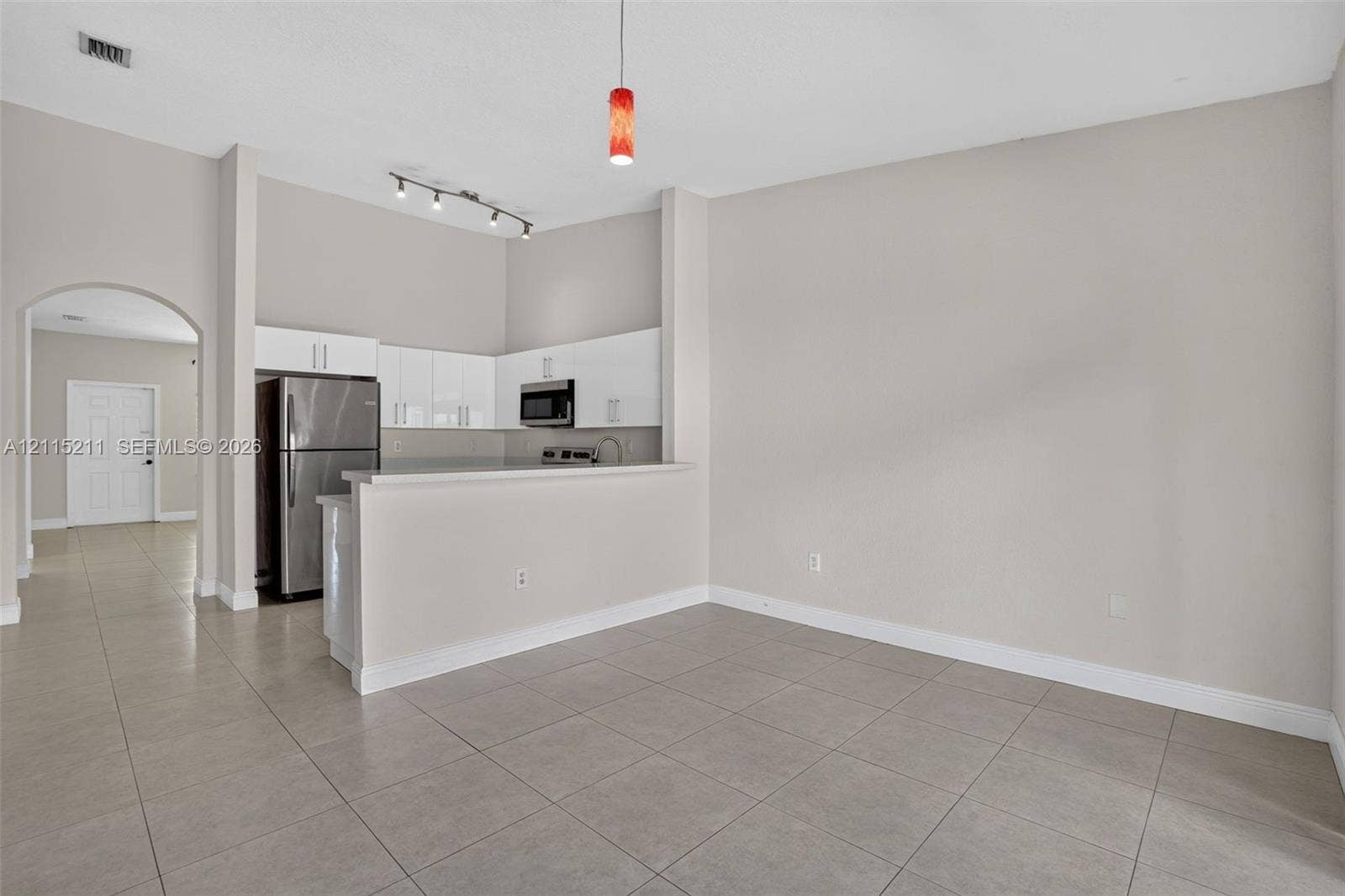 Kitchen featuring white flat-panel cabinetry, stainless steel appliances, a breakfast bar, and neutral floor tiling throughout