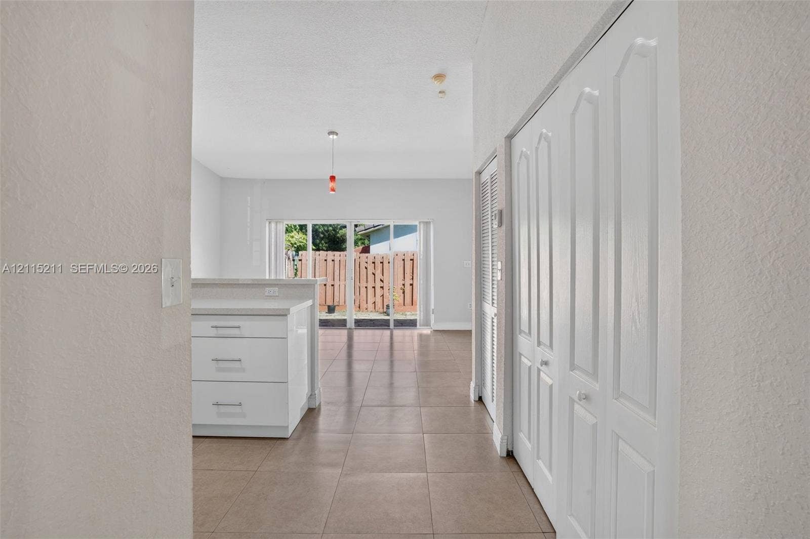 Ceramic tile flooring, white cabinetry with stone-finish countertops, and white paneled bifold closet doors