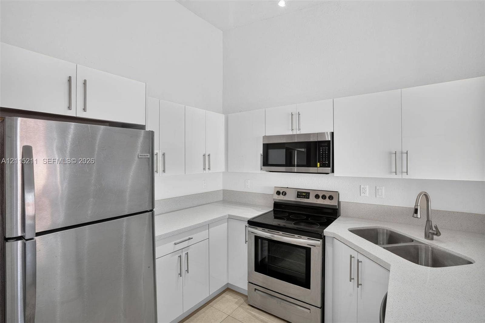 Kitchen featuring white cabinetry, quartz countertops, stainless steel appliances, and a dual-basin undermount sink with a gooseneck faucet