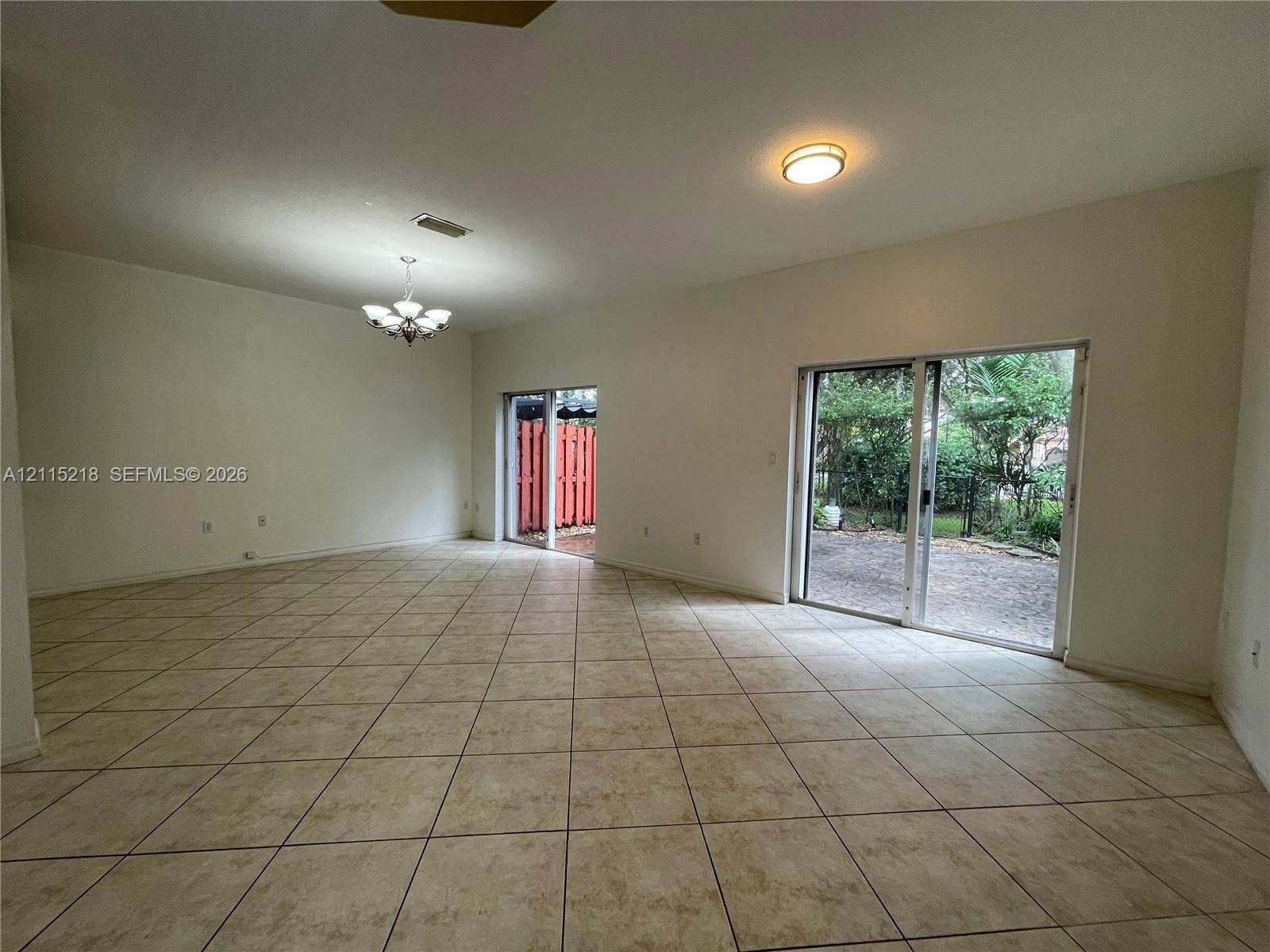 12738 SW 49th Court, #12738, Miramar, Miramar, FL 33027 Spacious interior featuring ceramic tile flooring, a recessed tray ceiling, a multi-light chandelier, and sliding glass doors leading to the exterior