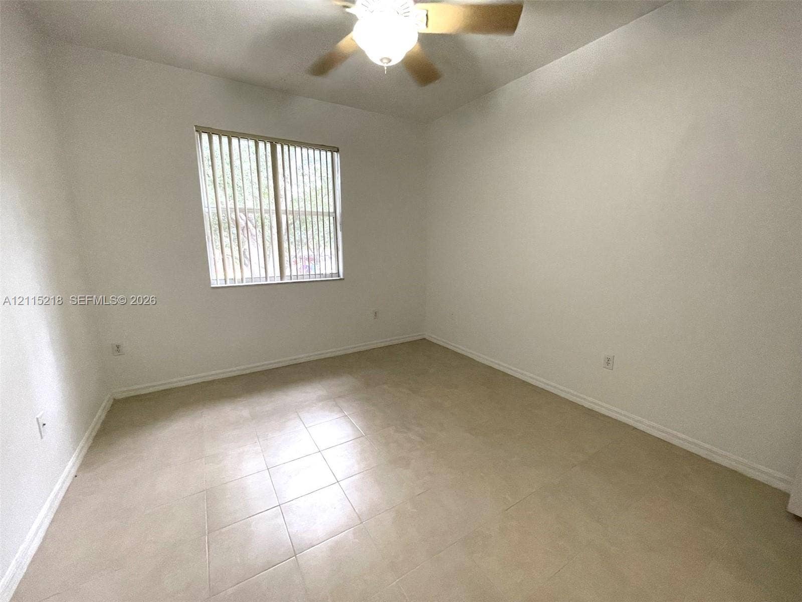 12738 SW 49th Court, #12738, Miramar, Miramar, FL 33027 Neutral-toned tile flooring, light-colored wall finish, ceiling-mounted fan with integrated lighting, and a single window featuring vertical blinds
