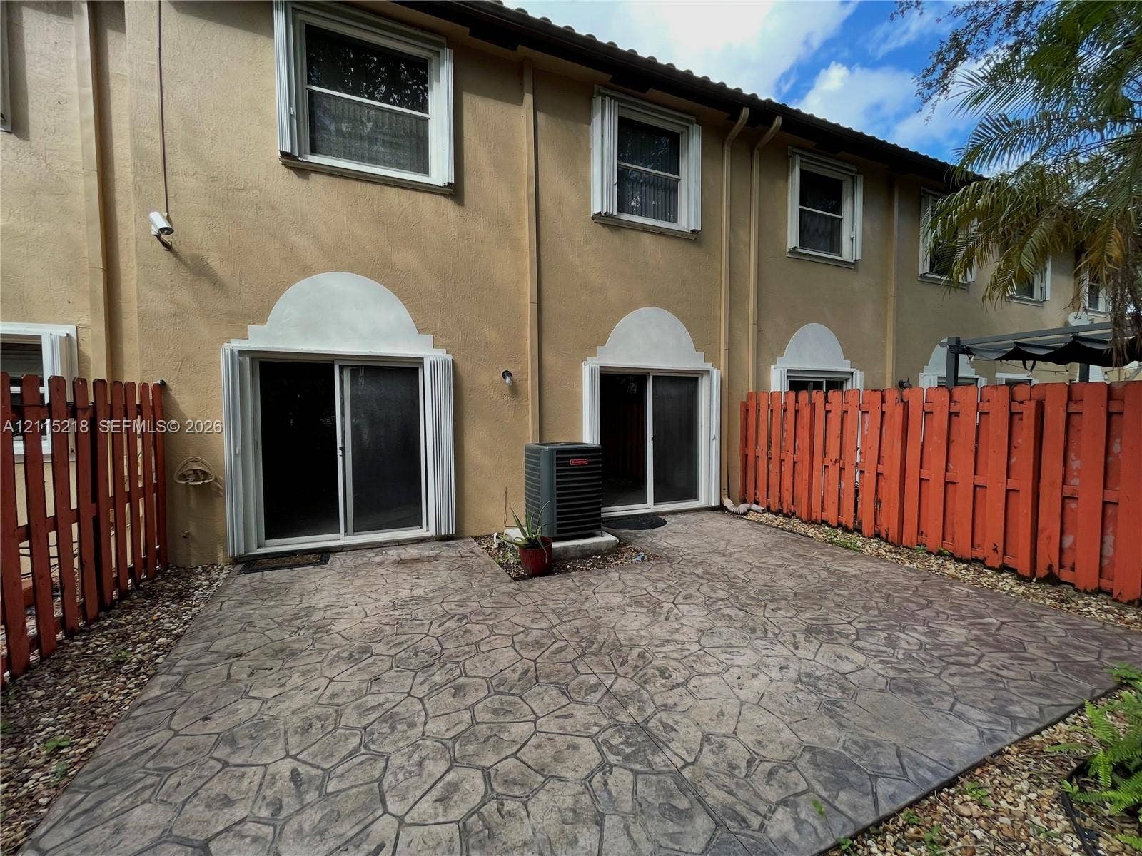 12738 SW 49th Court, #12738, Miramar, Miramar, FL 33027 Open-concept interior featuring neutral tile flooring, dual sliding glass doors, and a multi-arm chandelier
