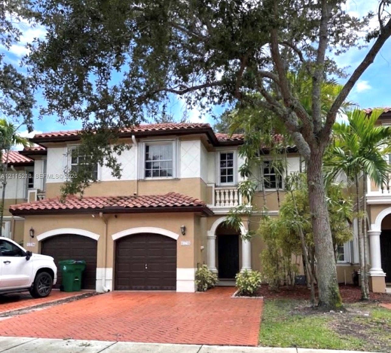12738 SW 49th Court, #12738, Miramar, Miramar, FL 33027 Two-story Mediterranean-style exterior featuring a terracotta tile roof, arched garage entries, stucco finish, stone-detailed balcony railing, and paved driveway