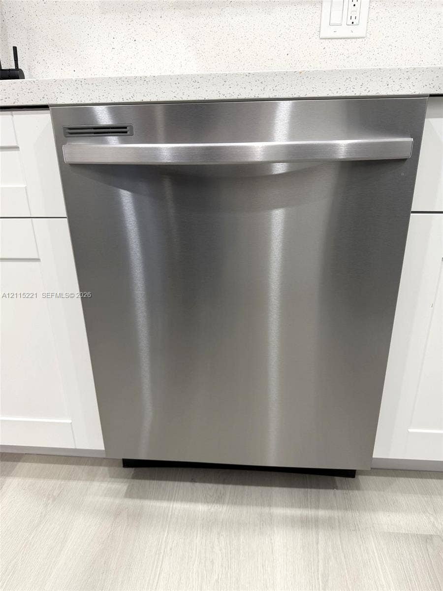 301 Bonaventure Boulevard, #15, Weston, FL 33326 Stainless steel dishwasher featuring a horizontal handle and integrated controls, accented by shaker-style cabinetry and a neutral-toned stone-finish countertop