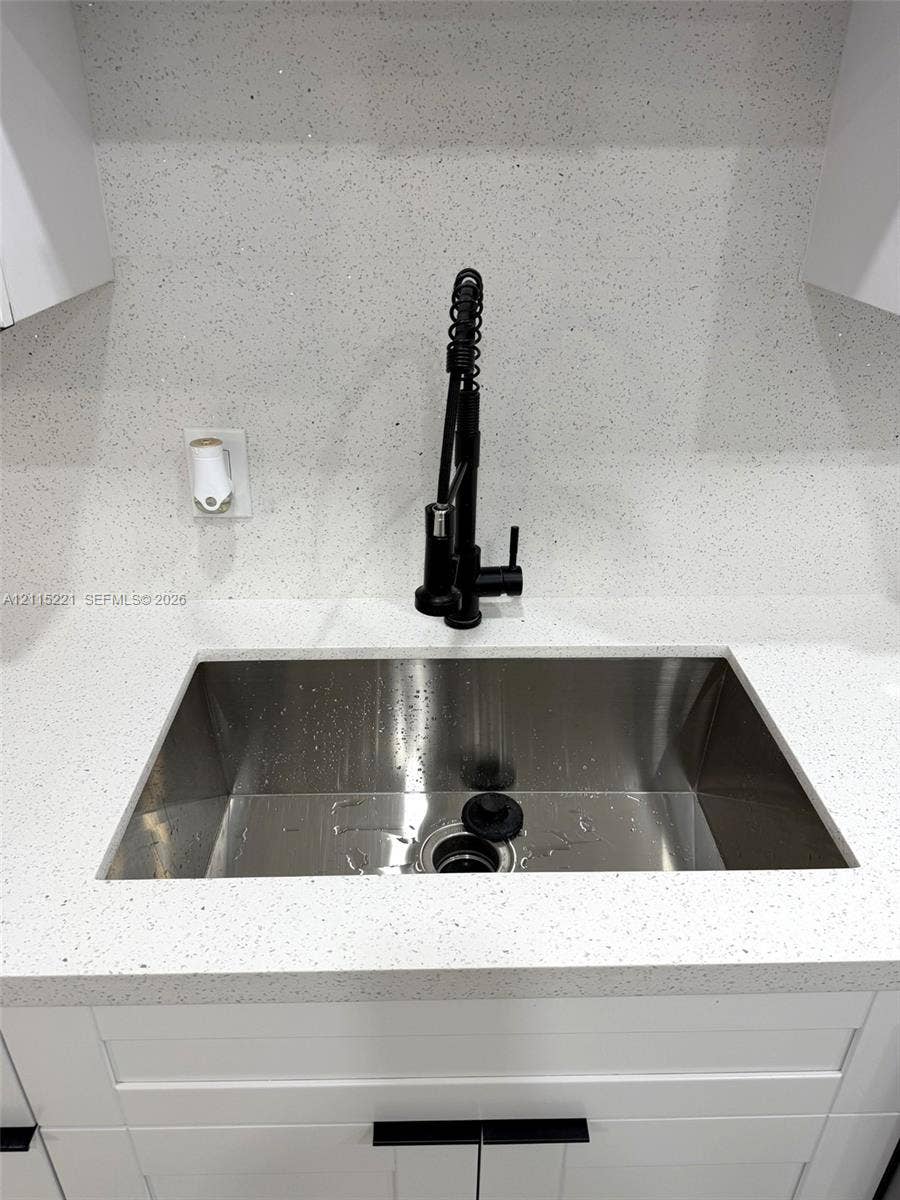 301 Bonaventure Boulevard, #15, Weston, FL 33326 Undermount stainless steel sink featuring a high-arc matte black pull-down faucet, white flecked stone-composite countertop, matching full-height backsplash, and shaker-style cabinetry with matte black hardware