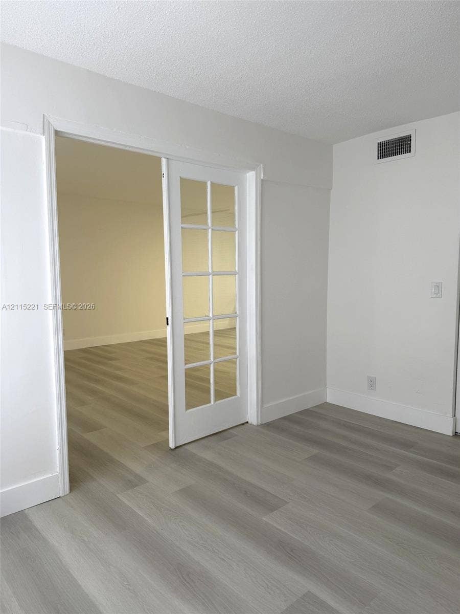 301 Bonaventure Boulevard, #15, Weston, FL 33326 Interior space featuring white-painted walls, wood-finish flooring, and a glass-paned French door
