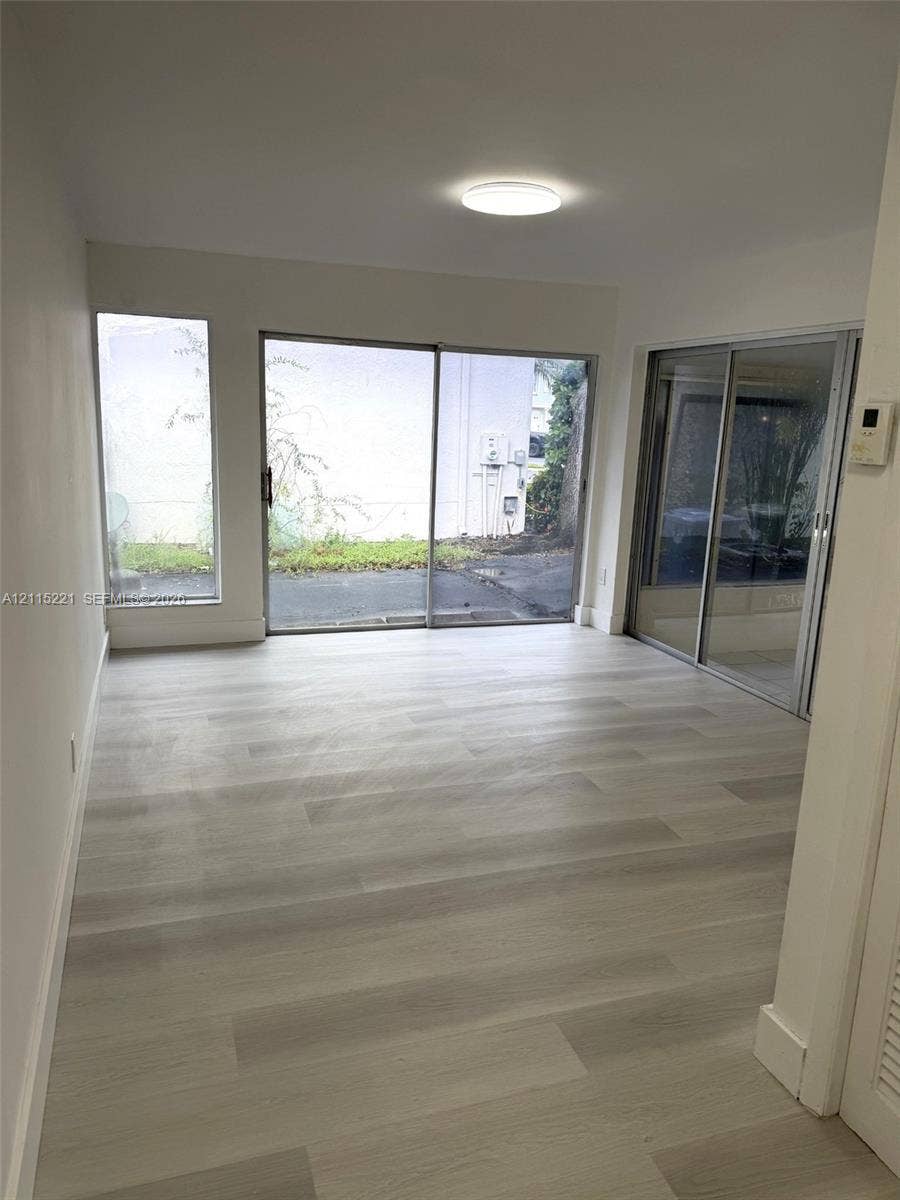 301 Bonaventure Boulevard, #15, Weston, FL 33326 Interior space featuring light-toned wood-finish flooring, dual sliding glass doors, a floor-to-ceiling side window, and a flush-mount overhead light fixture