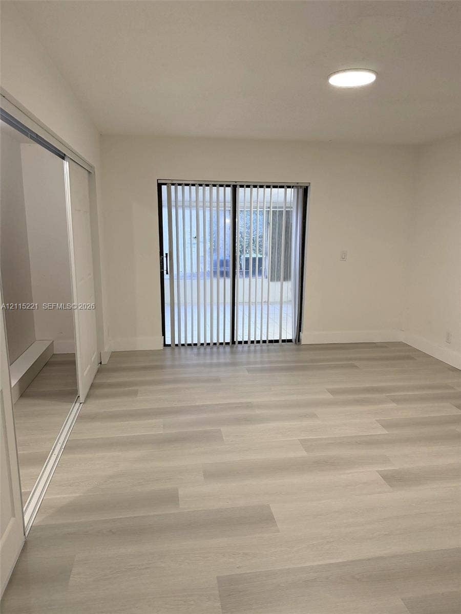 301 Bonaventure Boulevard, #15, Weston, FL 33326 Interior featuring wood-finish flooring, sliding glass doors with vertical blinds, a closet with mirrored sliding doors, and a flush-mount ceiling light