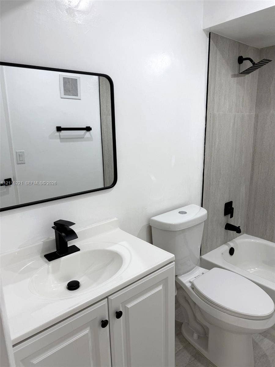 301 Bonaventure Boulevard, #15, Weston, FL 33326 Bathroom featuring a vanity with an integrated white countertop and sink, matte black hardware, a rectangular mirror with a black frame, and a tub with a vertical-tiled shower surround