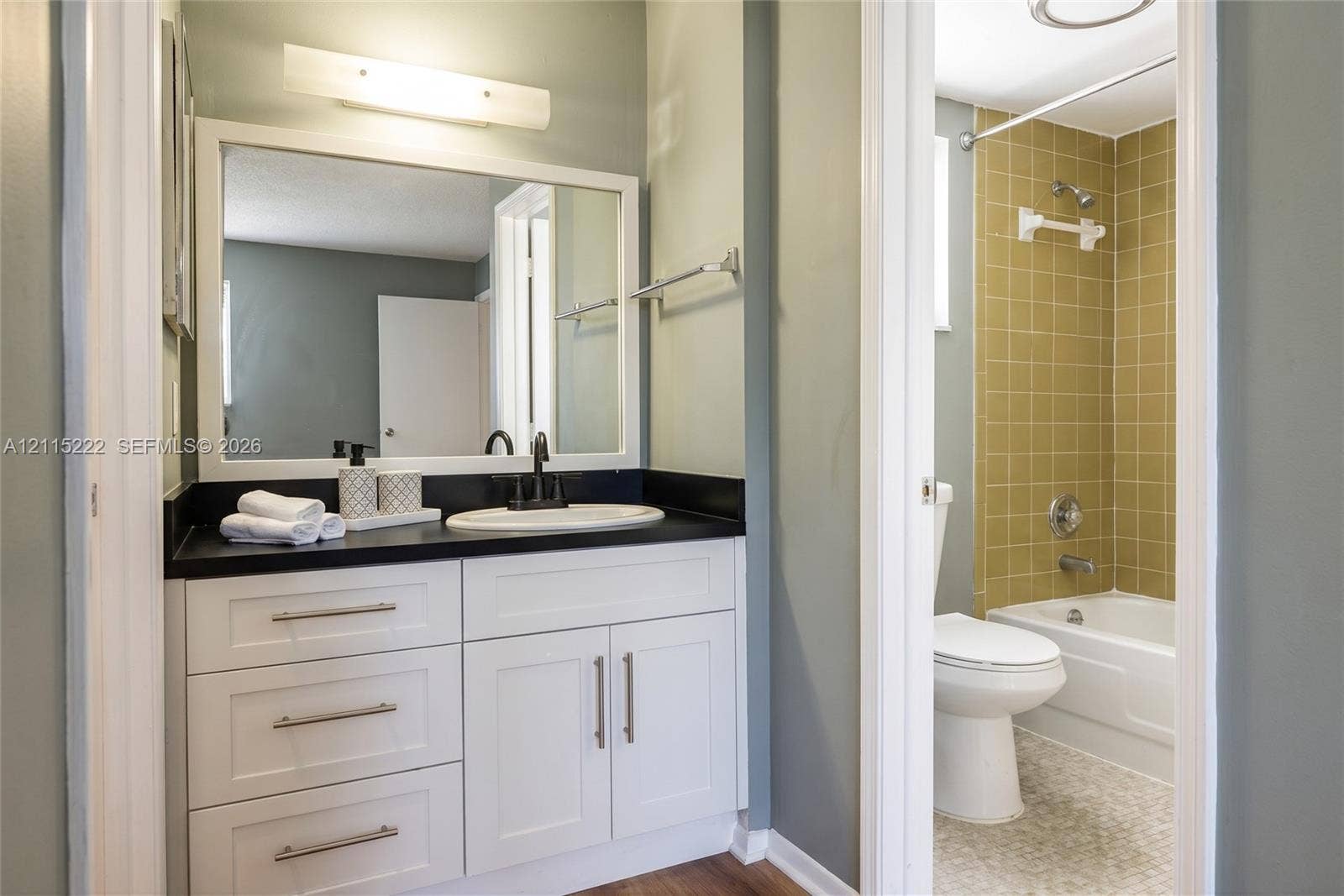 9450 Live Oak Place, #303, Davie, Davie, FL 33324 Bathroom featuring a white vanity with a dark countertop, undermount sink, matte black faucet, and full-width mirror, paired with a shower-tub combination featuring tiled walls