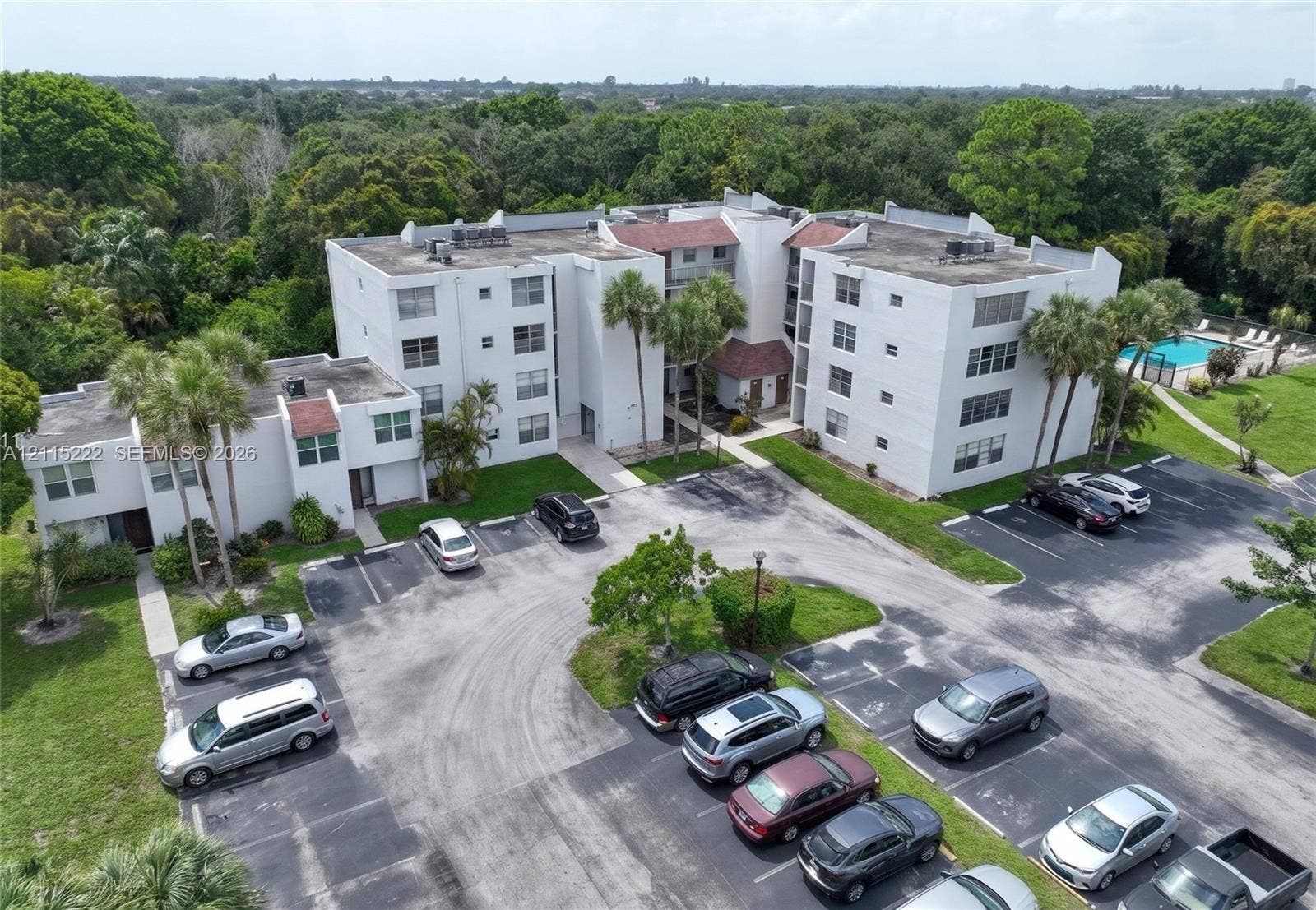 9450 Live Oak Place, #303, Davie, Davie, FL 33324 Multi-story residential building featuring a concrete exterior, pitched roof accents, dedicated asphalt parking, and an on-site swimming pool