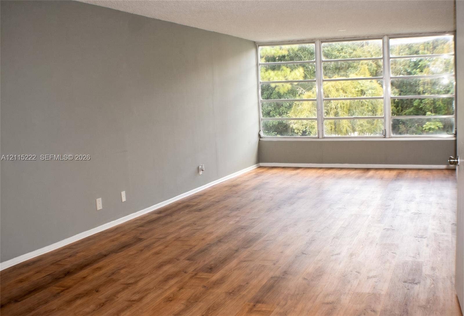 9450 Live Oak Place, #303, Davie, Davie, FL 33324 Spacious interior featuring wood-finish flooring, neutral wall paint, and floor-to-ceiling metal-framed windows