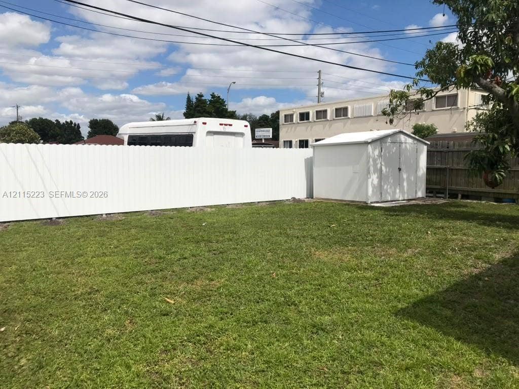 737 SE 8th Place, Hialeah, FL 33010 Fenced backyard featuring a manicured lawn and an exterior storage structure