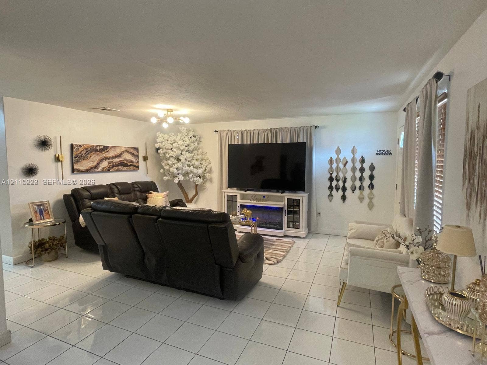 737 SE 8th Place, Hialeah, FL 33010 Open-concept living space featuring high-gloss tile flooring and a multi-light modern chandelier