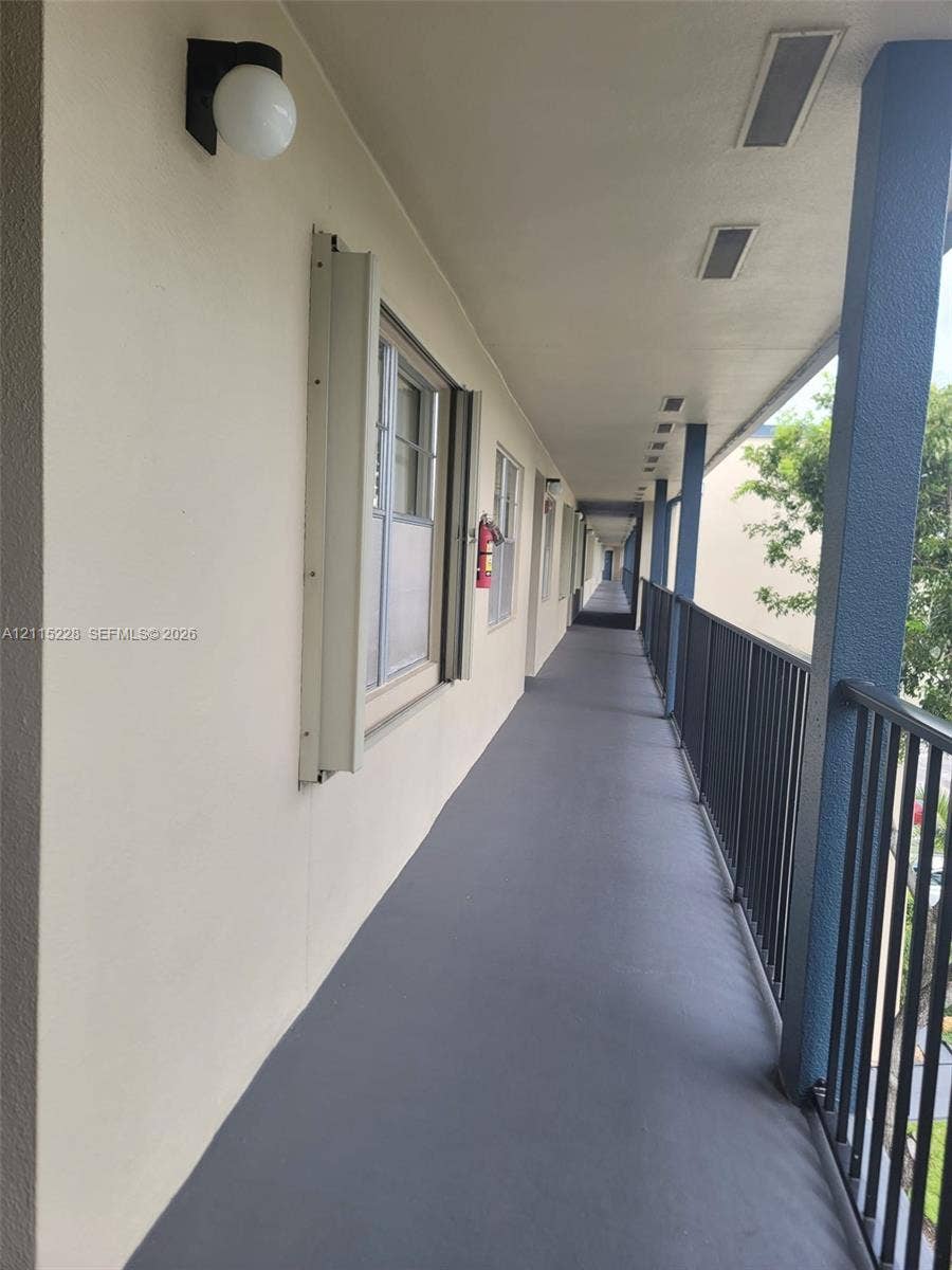 12950 SW 7th Court, #404A, Pembroke Pines, Pembroke Pines, FL 33027 Exterior corridor featuring covered walkway, protective metal railing, surface-mounted globe lighting, and inset ceiling fixtures