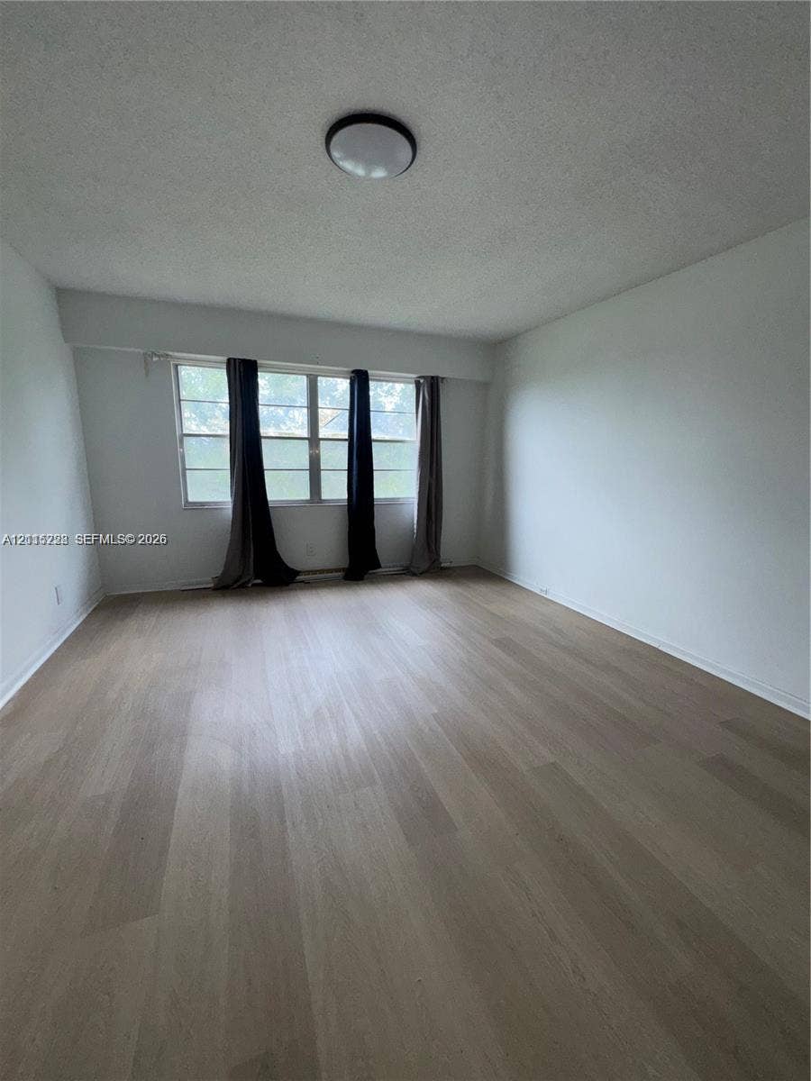 12950 SW 7th Court, #404A, Pembroke Pines, Pembroke Pines, FL 33027 Interior room featuring wood-finish flooring, white walls, large multi-pane windows, and a circular flush-mount ceiling light fixture
