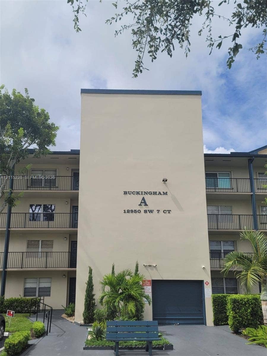 12950 SW 7th Court, #404A, Pembroke Pines, Pembroke Pines, FL 33027 Multi-story residential building featuring smooth stucco exterior, decorative metal balcony railings, and ground-level garage access