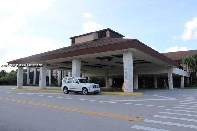 12950 SW 7th Court, #404A, Pembroke Pines, Pembroke Pines, FL 33027 Covered porte-cochre entrance featuring stone-clad structural columns and a wide paved driveway