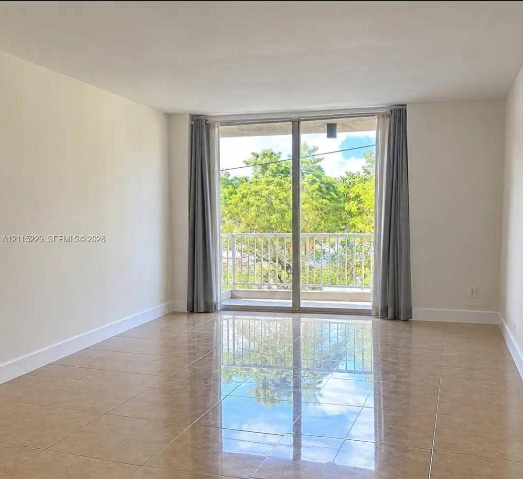 2020 NE 135th Street, #211, North Miami, FL 33181 Large-format tile flooring, expansive sliding glass doors, and a private balcony featuring a metal railing