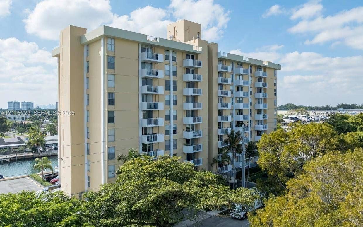 2020 NE 135th Street, #211, North Miami, FL 33181 High-rise condominium building featuring multi-level private balconies, smooth exterior cladding, and waterside positioning