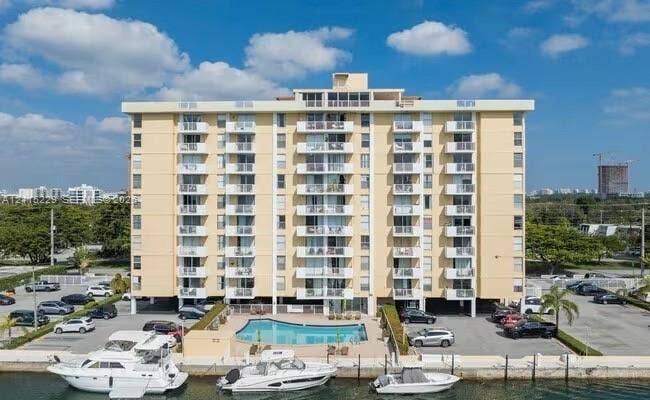 2020 NE 135th Street, #211, North Miami, FL 33181 Multi-story residential building featuring exterior balconies, an in-ground swimming pool, and concrete bulkhead boat slips