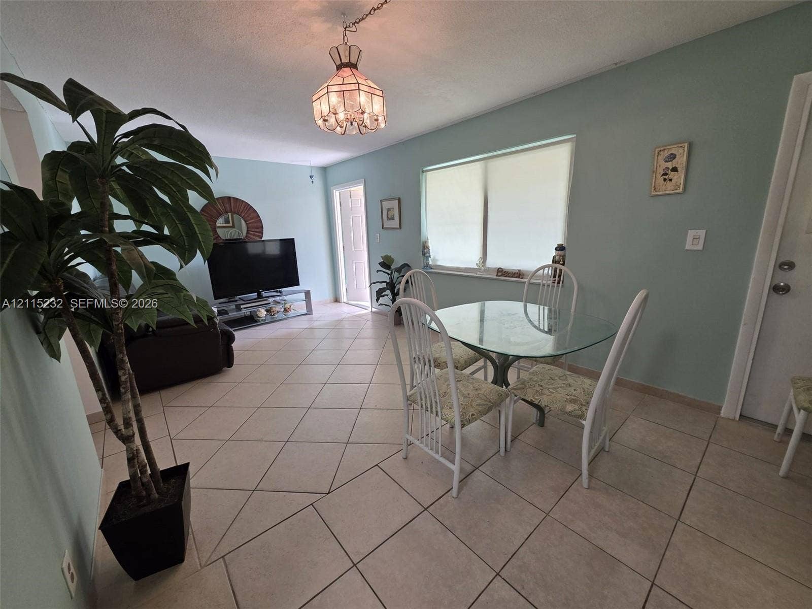 Open-concept interior featuring large-format ceramic tile flooring, neutral wall paint, and a decorative pendant light fixture