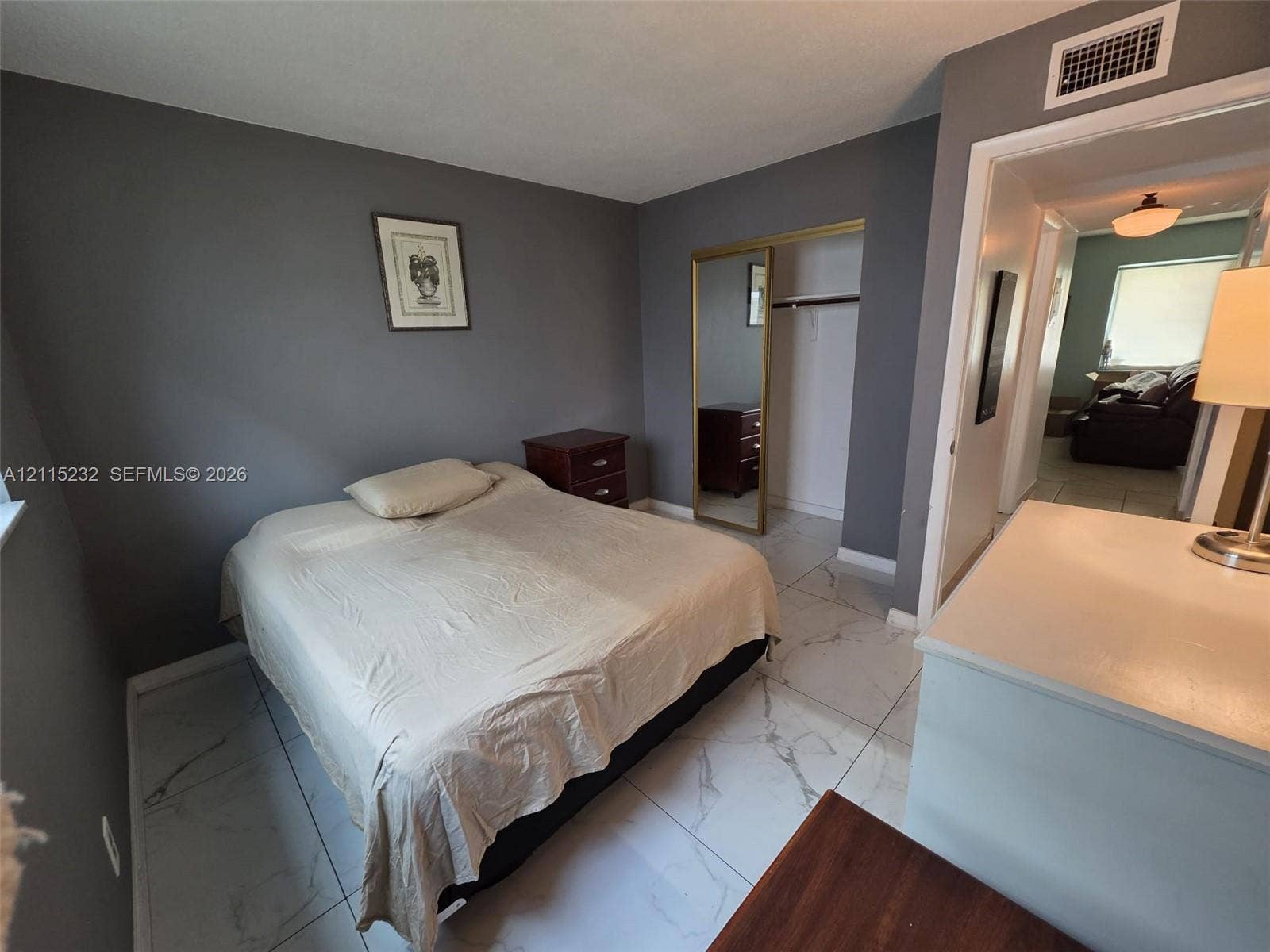 Large-format neutral tile flooring and closet featuring a floor-to-ceiling mirrored sliding door
