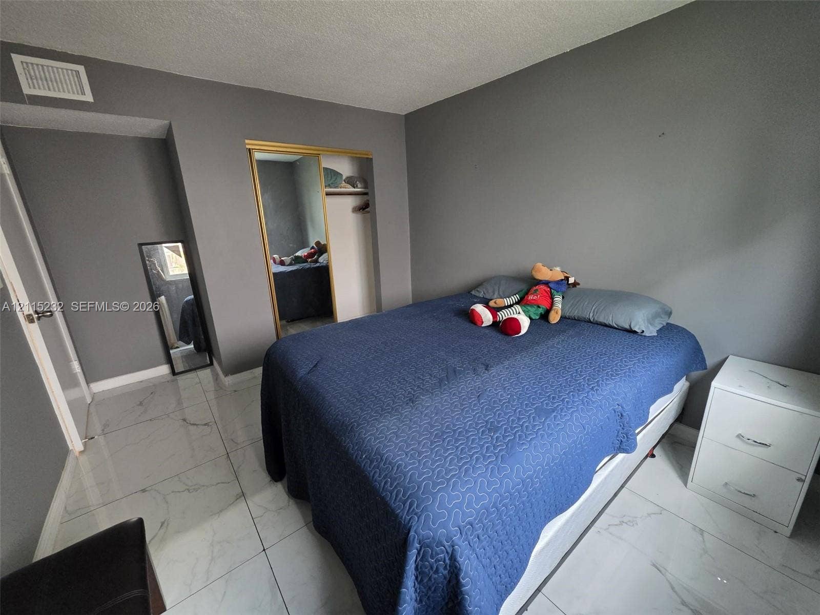 Large-format stone-finish floor tiling, sliding mirrored closet doors, and neutral wall tones