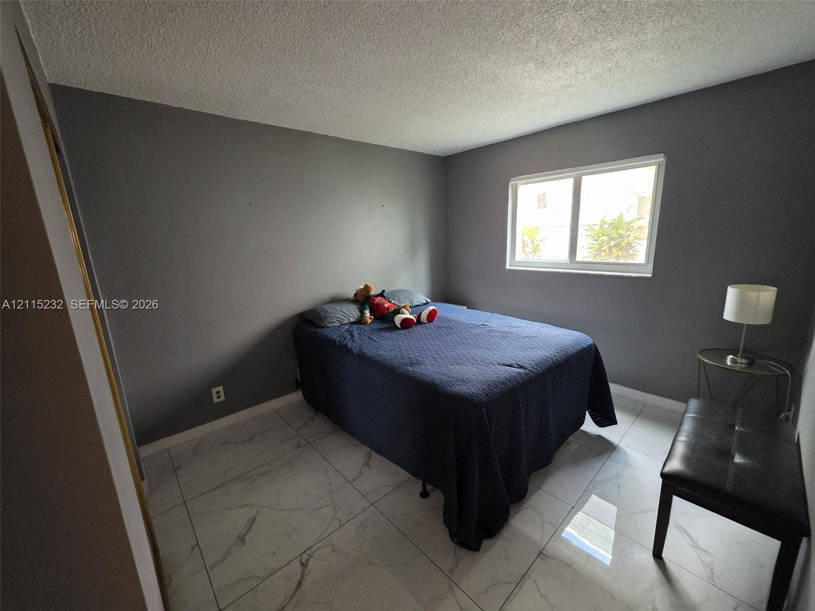 Neutral-toned interior space featuring large-format stone-finish tile flooring and a horizontal slider window