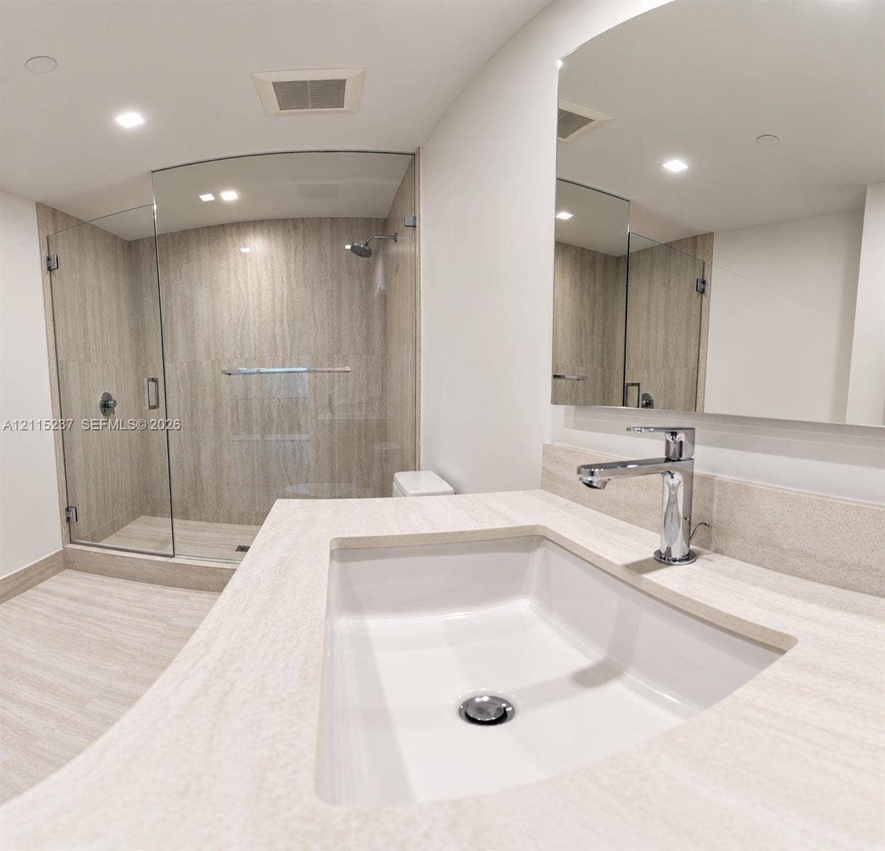 2411 Laguna Circle, #802, North Miami, North Miami, FL 33181 Bathroom featuring a vanity with an integrated rectangular sink and polished chrome faucet, stone-finish countertop, frameless glass shower enclosure, and stone-finish wall tile