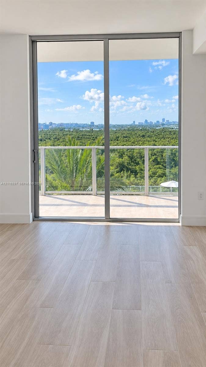 2411 Laguna Circle, #802, North Miami, North Miami, FL 33181 Full-height sliding glass doors with aluminum framing, wood-finish flooring, and a private balcony featuring a glass railing