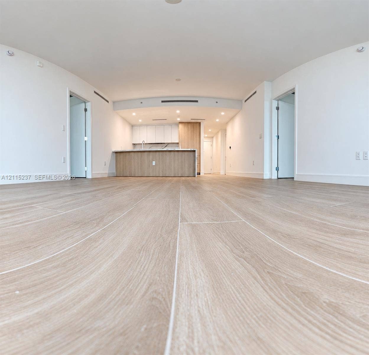 2411 Laguna Circle, #802, North Miami, North Miami, FL 33181 Open-concept interior featuring light wood-finish flooring, recessed lighting, and a kitchen island with stone-finish countertops and wood-grain cabinetry