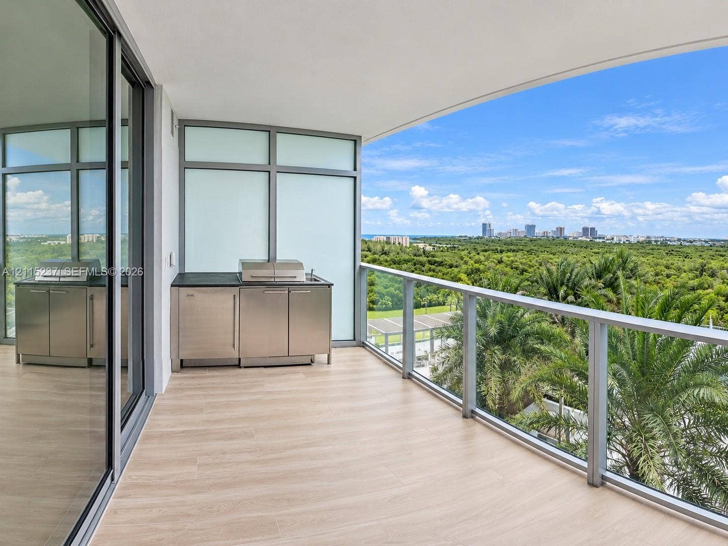 2411 Laguna Circle, #802, North Miami, North Miami, FL 33181 Covered balcony featuring wood-finish flooring, stainless steel outdoor kitchen cabinetry, built-in grill, glass railing, and floor-to-ceiling sliding glass doors