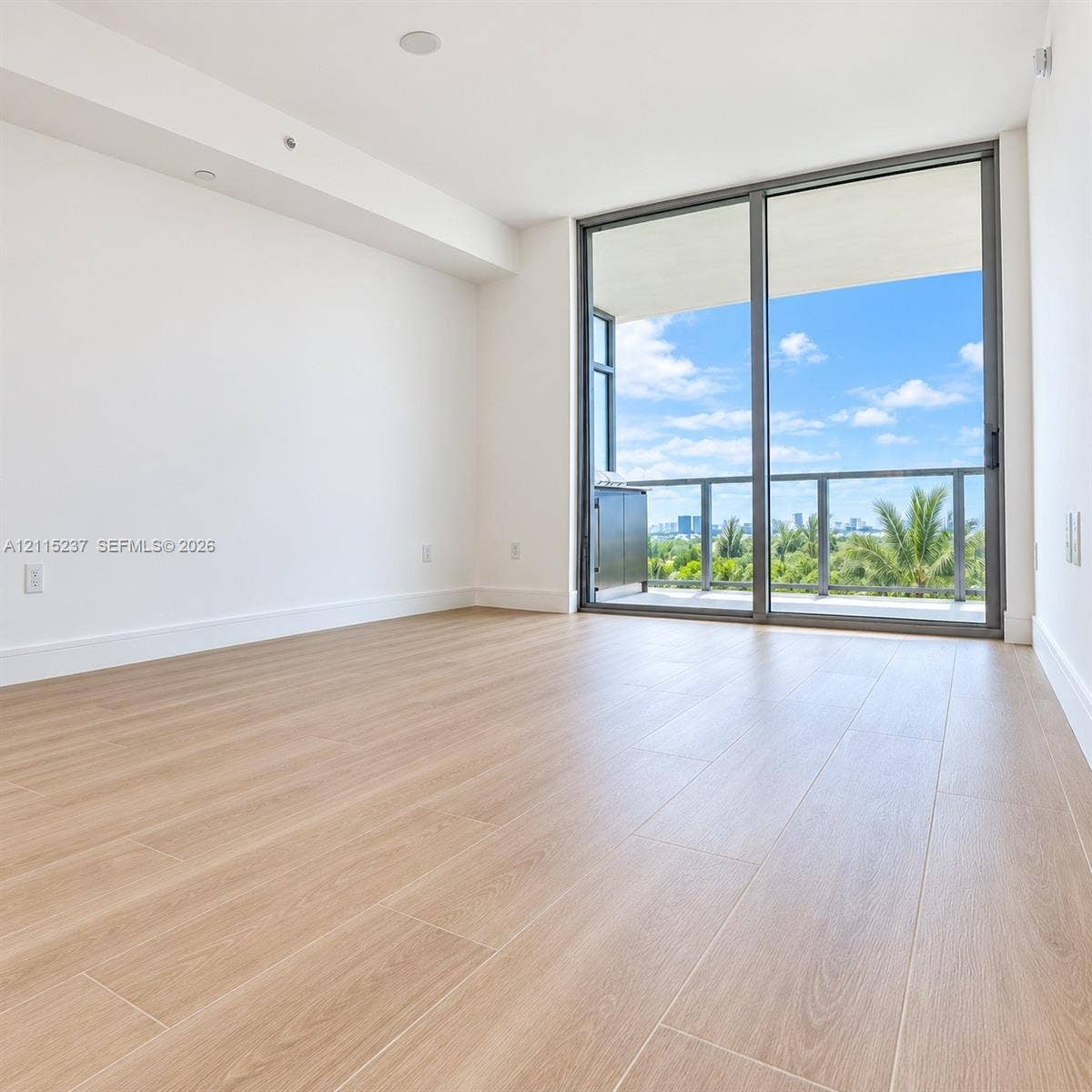 2411 Laguna Circle, #802, North Miami, North Miami, FL 33181 Interior room featuring wood-finish flooring, floor-to-ceiling glass sliding doors, and a private balcony with metal railings
