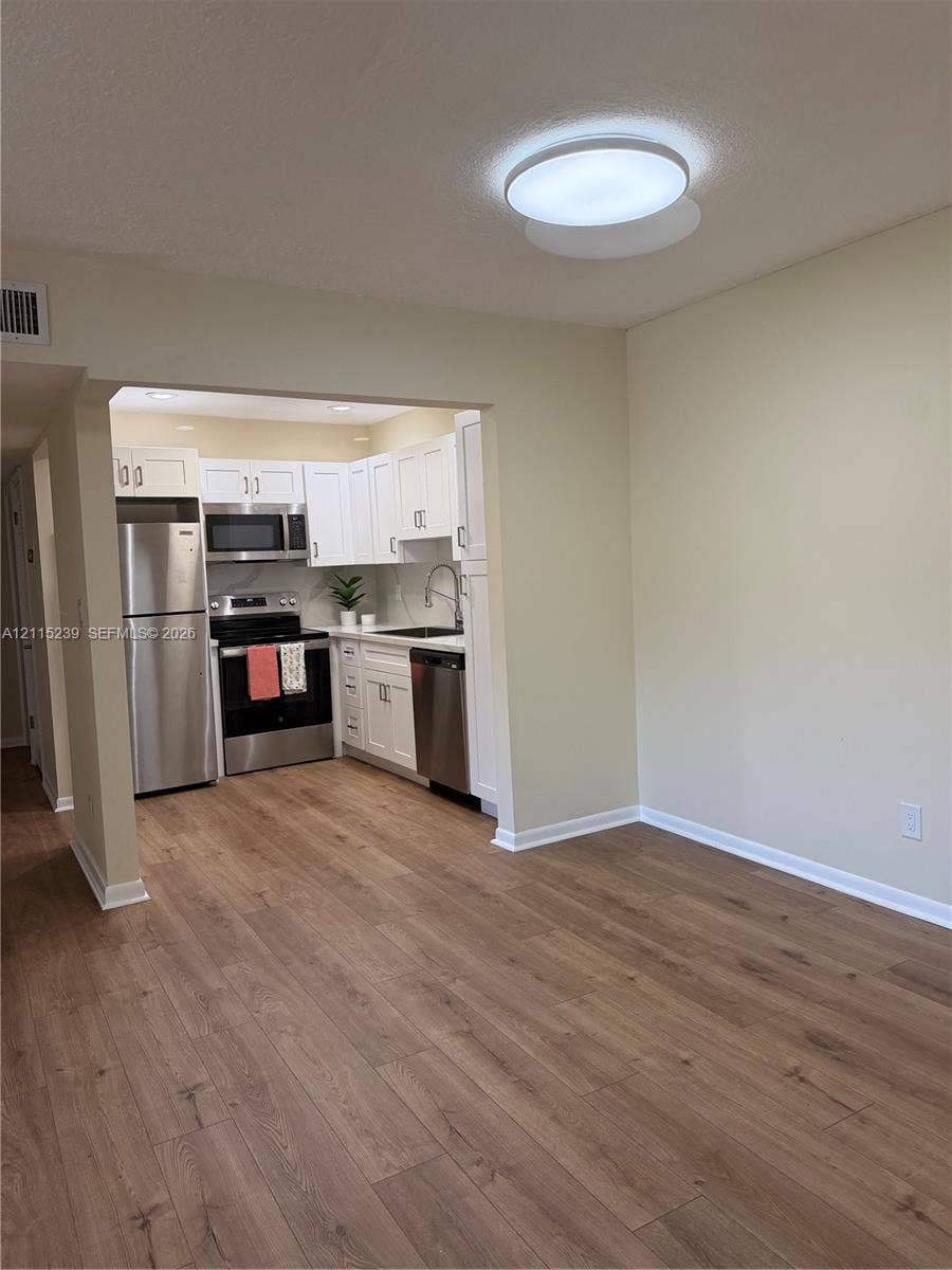 9015 SW 138th Street, #16-2, Miami, Miami, FL 33176 Kitchen featuring white shaker-style cabinetry, stainless steel appliances, and wood-finish flooring throughout