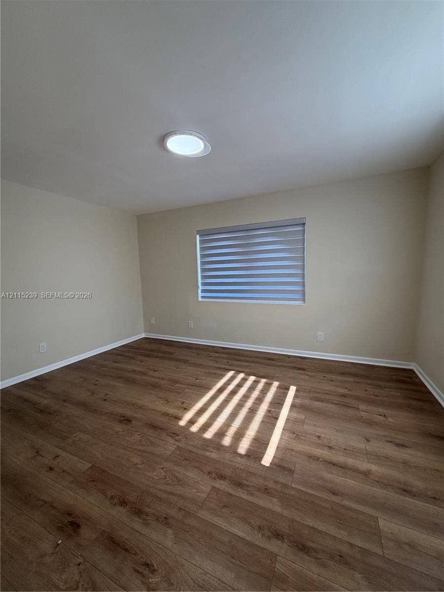 9015 SW 138th Street, #16-2, Miami, Miami, FL 33176 Neutral interior space featuring wood-finish flooring, a flush-mount ceiling light fixture, and a window with installed roller shades