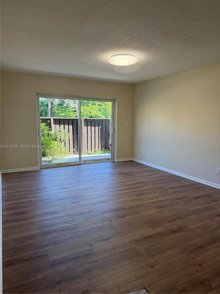 9015 SW 138th Street, #16-2, Miami, Miami, FL 33176 Room interior featuring wood-finish flooring, neutral wall paint, and a sliding glass door with a metal frame