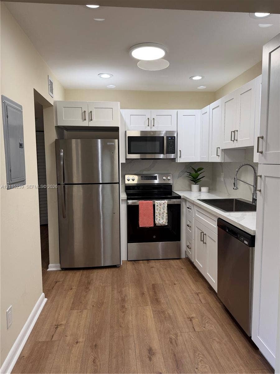 9015 SW 138th Street, #16-2, Miami, Miami, FL 33176 Kitchen featuring white shaker-style cabinetry, stainless steel appliances, wood-finish flooring, quartz countertops, and a gooseneck faucet