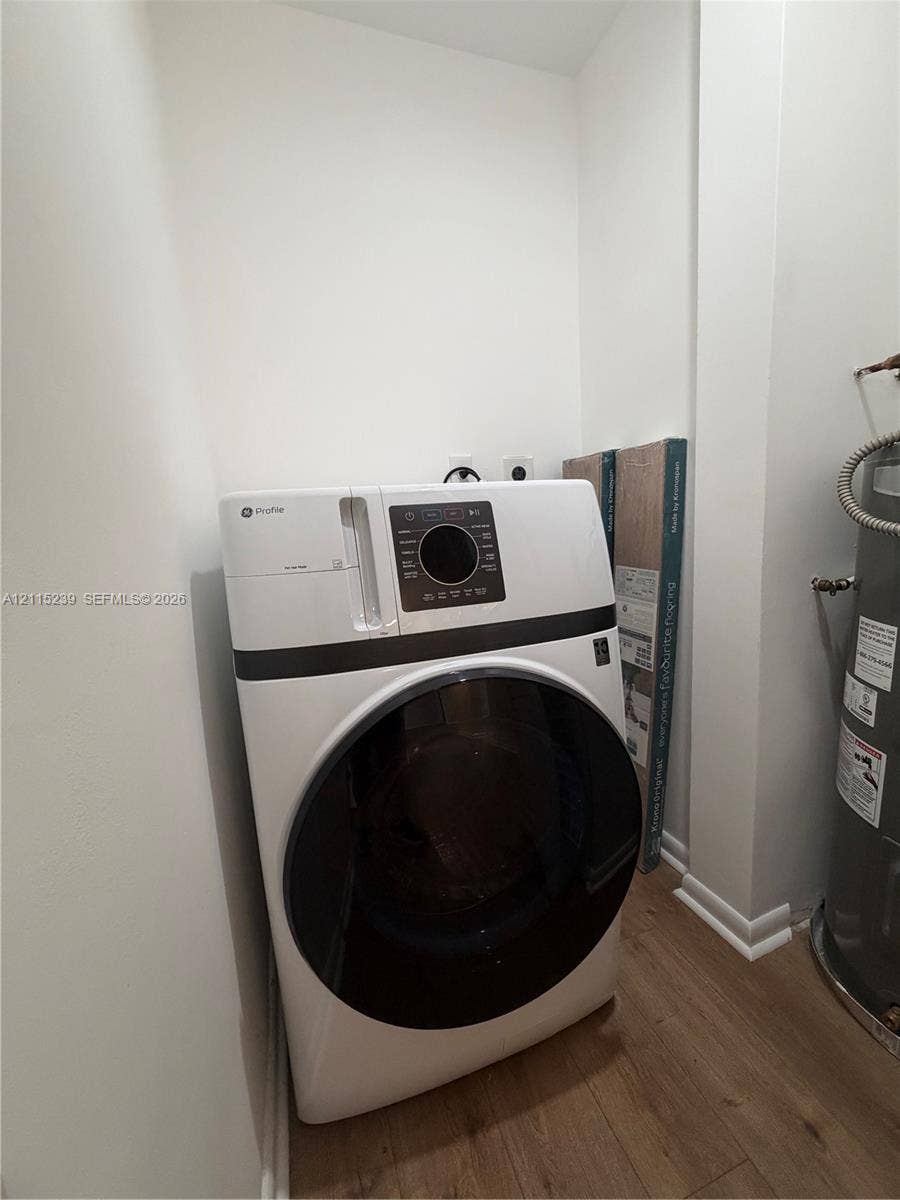 9015 SW 138th Street, #16-2, Miami, Miami, FL 33176 Utility area featuring a white front-load washer, wood-finish flooring, and a dedicated water heater