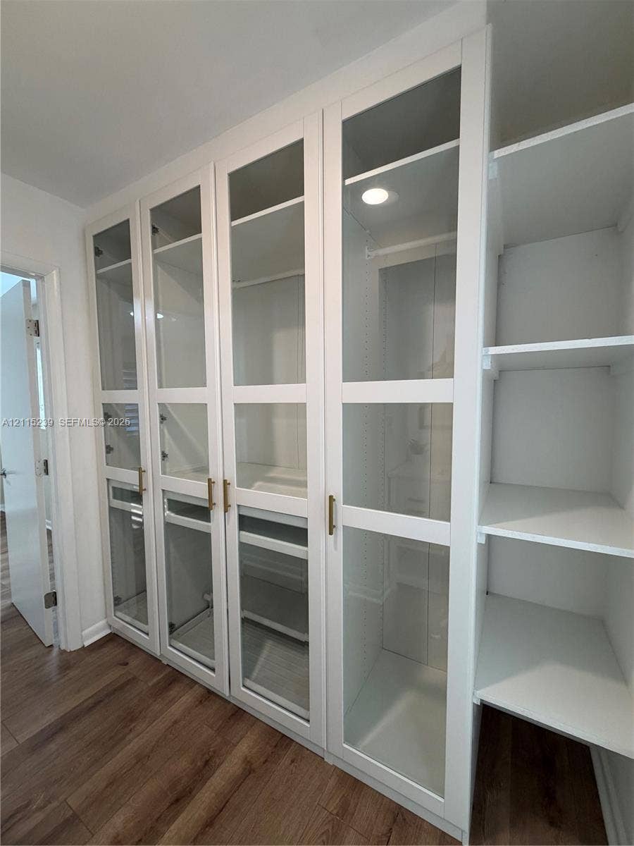 9015 SW 138th Street, #16-2, Miami, Miami, FL 33176 Built-in floor-to-ceiling cabinetry featuring glass-panel doors, brass hardware, integrated recessed lighting, and wood-finish flooring