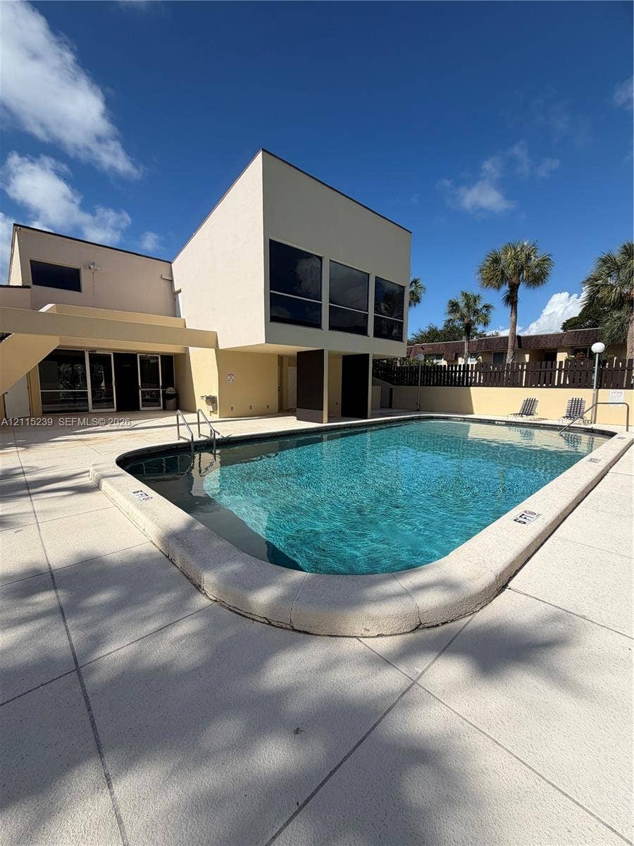 9015 SW 138th Street, #16-2, Miami, Miami, FL 33176 In-ground swimming pool featuring a curved concrete deck, metal pool ladder, and surrounding privacy fencing