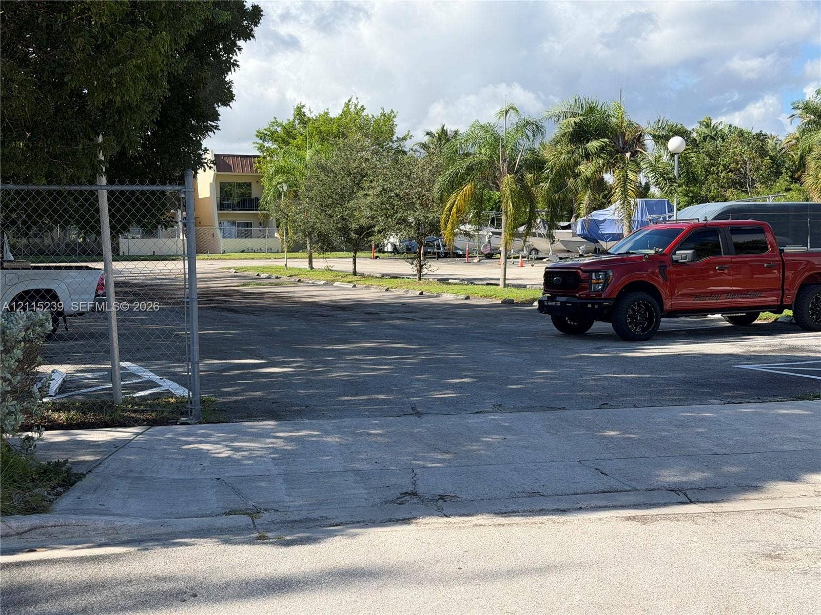 9015 SW 138th Street, #16-2, Miami, Miami, FL 33176 Paved surface parking lot featuring chain-link perimeter fencing and mature palm tree landscaping