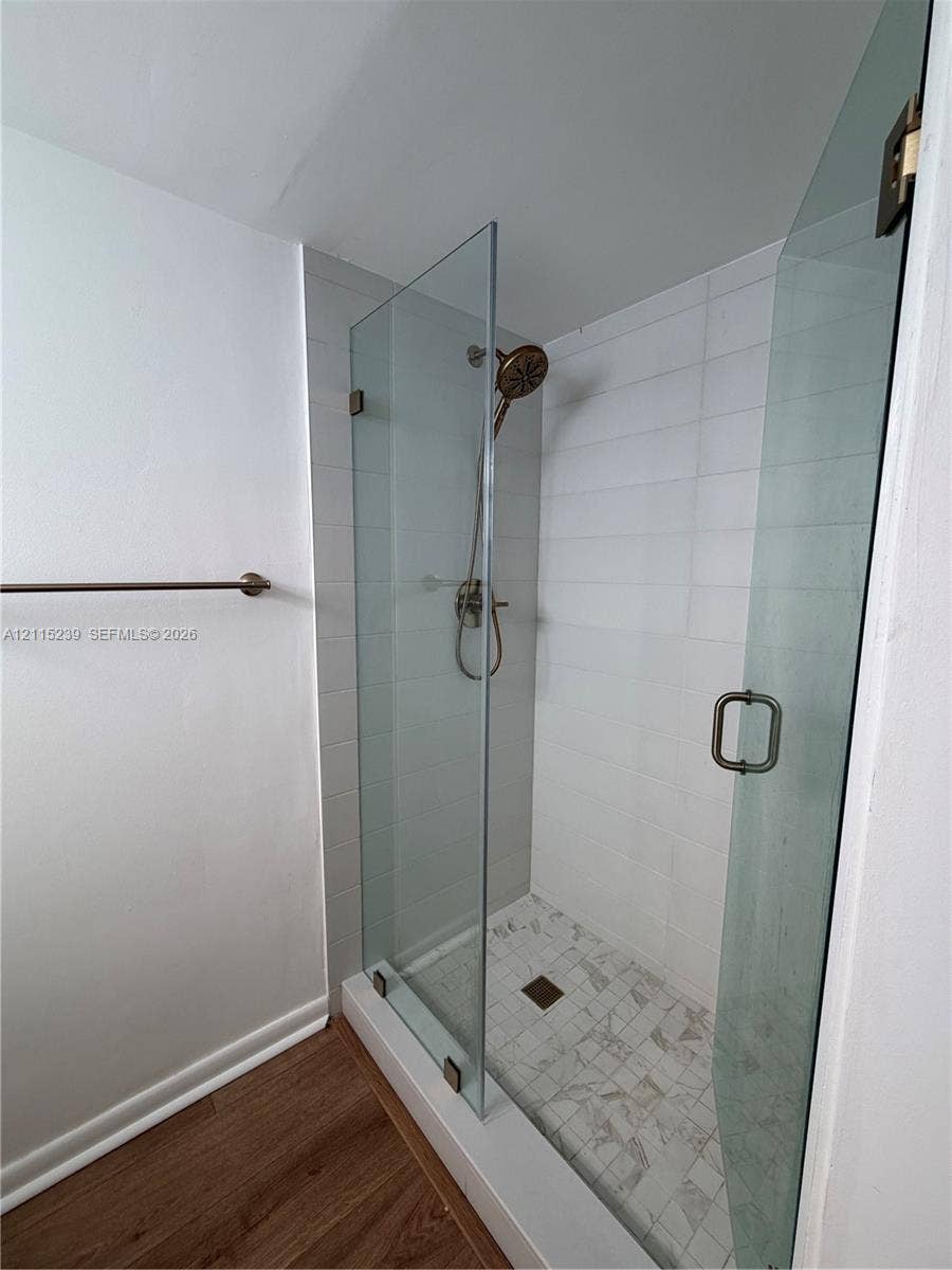 9015 SW 138th Street, #16-2, Miami, Miami, FL 33176 Walk-in shower featuring a frameless glass enclosure, white rectangular wall tile, stone-finish floor tile, and bronze-tone fixtures