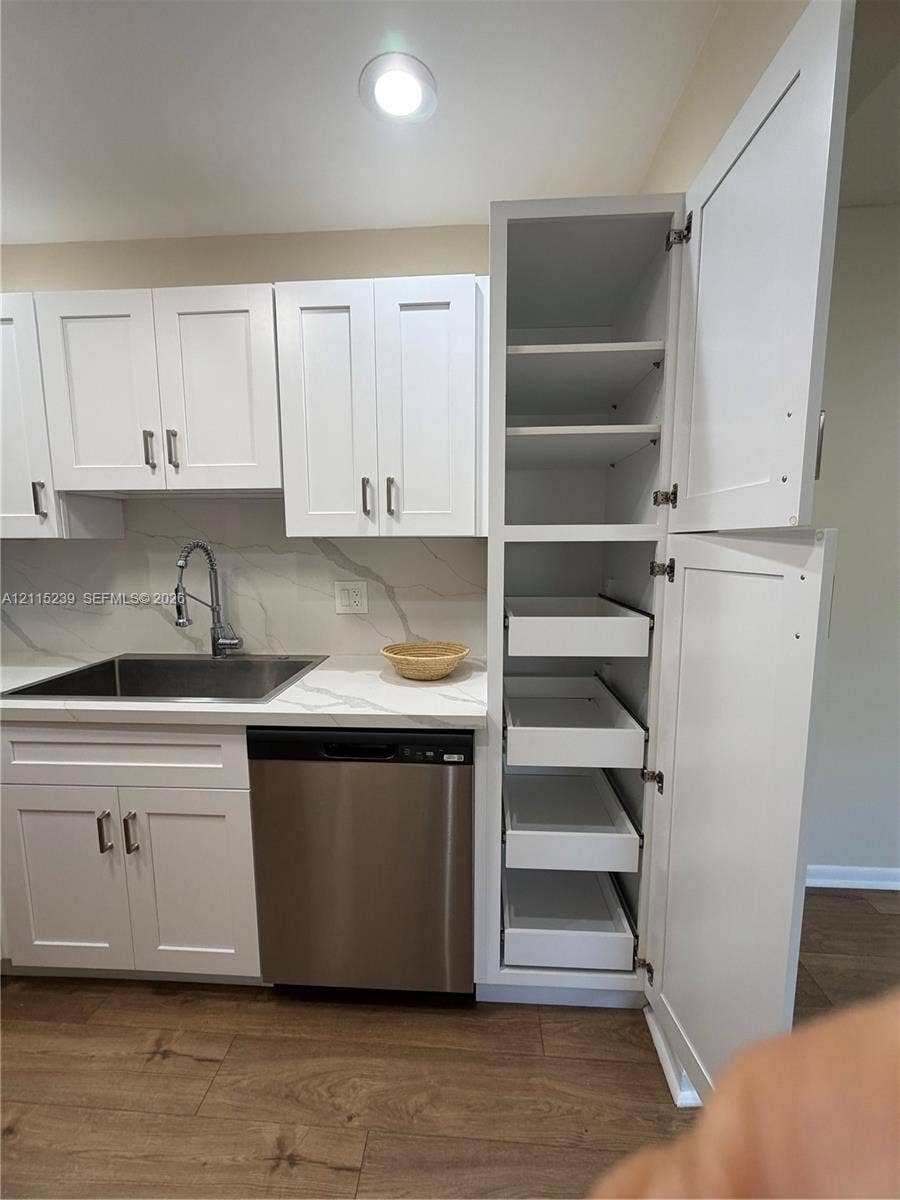 9015 SW 138th Street, #16-2, Miami, Miami, FL 33176 Shaker-style white cabinetry featuring a floor-to-ceiling pantry with pull-out drawers, stone-finish countertops, stainless steel undermount sink, high-arc faucet, and wood-finish flooring