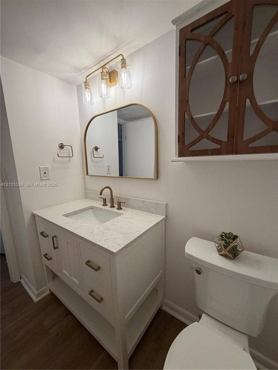 9015 SW 138th Street, #16-2, Miami, Miami, FL 33176 White vanity with stone-composite countertop, arched-top mirror, brass-finish fixtures, and custom-inlay wall cabinetry